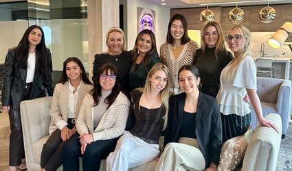 women posing for photo, some standing and some sitting on sofa