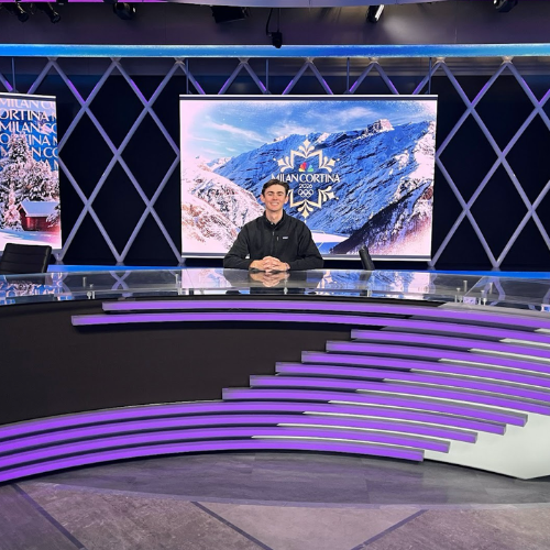 Farrell sits at NBC Sports desk.